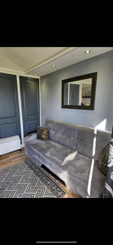 un sofá gris en una sala de estar con espejo en 2 Bedroom Chalet Isle of Sheppey Holiday Village, en Kent