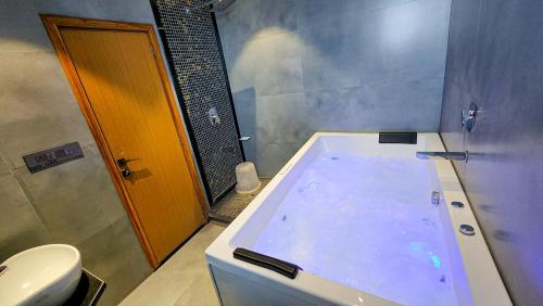 Hotel Nova Boutique في راجكوت: حمام مع حوض كبير ومرحاض