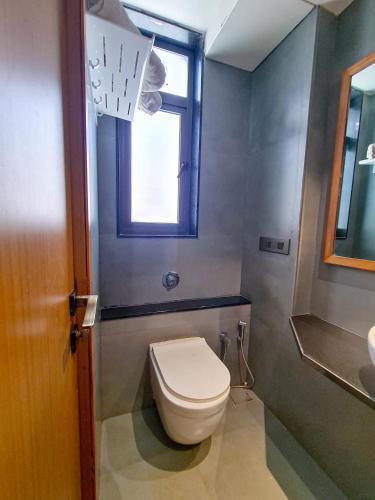 a bathroom with a toilet and a window at Hotel Nova Boutique in Rajkot