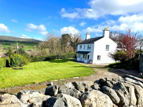 une maison blanche sur une colline avec des rochers dans l'établissement Garth- Stunning Scenic semi-rural Cottage with Games room, à Conwy
