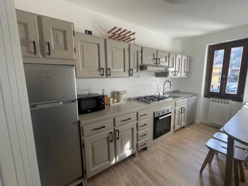 una cocina con armarios blancos y electrodomésticos de acero inoxidable en Appartamento Mountain Paradise Ponte di Legno Tonale, en Ponte di Legno