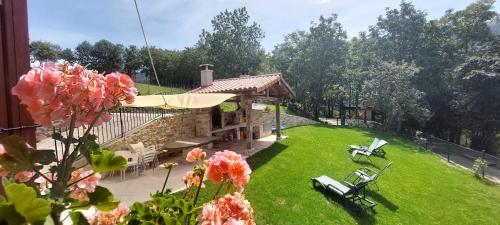 a backyard with a house and a yard with pink flowers at CASA RURAL Arriaran in Leitza