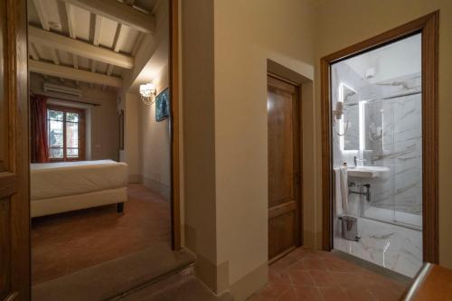 a hallway with a bathroom with a bed and a mirror at Hotel Palazzo San Niccolò & Spa in Radda in Chianti
