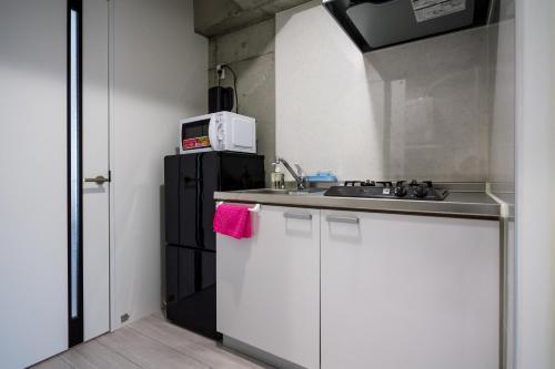 a small kitchen with a sink and a microwave at ALBERGO Pino 泊 in Tomari