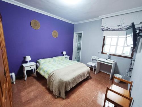een slaapkamer met een bed en een paarse muur bij Rincón de Joel Habitación con baño privado in La Orotava