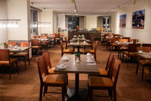 ハンブルクにあるノヴム ホテル グラフ モルトケ ハンブルクのテーブルと椅子が並ぶダイニングルーム