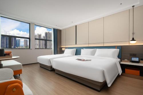 two beds in a hotel room with large windows at Yizhi Hotel - Guangzhou East Railway Station Tianhe Sports Center in Guangzhou