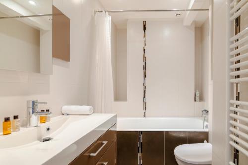 ein Badezimmer mit einer Badewanne, einem WC und einem Waschbecken in der Unterkunft Veeve - Chaillot Skies in Paris