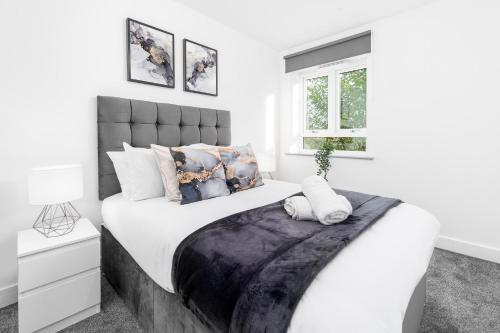 a white bedroom with a large bed with white sheets and pillows at Smethwick Deluxe 2 Bedroom Aparetment - Secure Parking - Balcony - Rated Exceptional - 9MC in Birmingham
