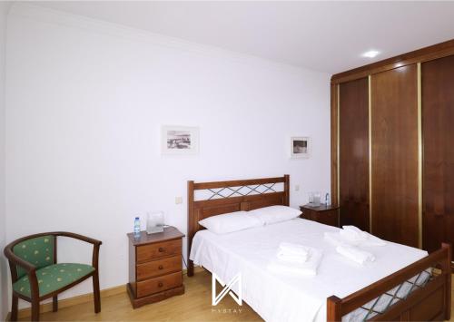 a bedroom with a large bed with a chair and a dresser at MyStay - Casa Pereira Soeima in Alfândega da Fé
