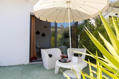 uma mesa e cadeiras com um guarda-sol e copos de vinho em Natur Hotel Tanca em Cardedu