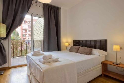 Comfortable 4 rooms 2Bath w balcony في برشلونة: غرفة نوم بسرير كبير عليها مناشف