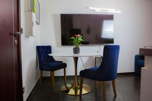 une table avec deux chaises bleues et un vase avec des fleurs dans l'établissement Studio Paisible proche de Paris et Disneyland, à Neuilly-sur-Marne