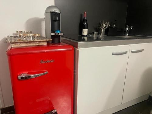- un réfrigérateur rouge dans la cuisine avec évier dans l'établissement Studio Paisible proche de Paris et Disneyland, à Neuilly-sur-Marne