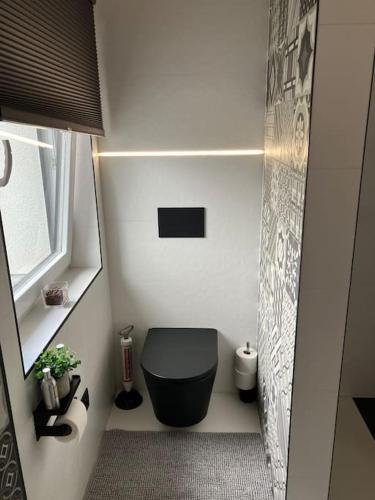 a small bathroom with a black toilet in a room at La maison de Timao in Hannut
