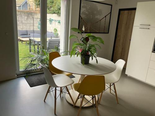 una mesa blanca y sillas con una maceta. en La maison de Timao, en Hannut
