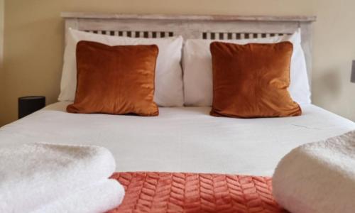 a bed with two orange pillows and a white bedspread at Manor Place in Broughty Ferry