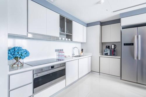 a kitchen with white cabinets and a stainless steel refrigerator at Marina Skyline View & Dubai Harbour Beachfront in Dubai