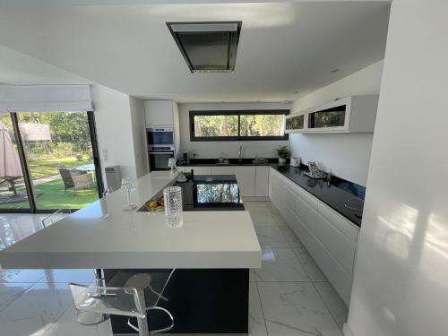 une cuisine avec des armoires blanches et un comptoir dans l'établissement Superbe villa contemporaine avec piscine et climatisation - FR-1-776-82, à Argelès-sur-Mer