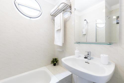 a white bathroom with a sink and a bath tub at Apartamento Fabi in Puerto Naos