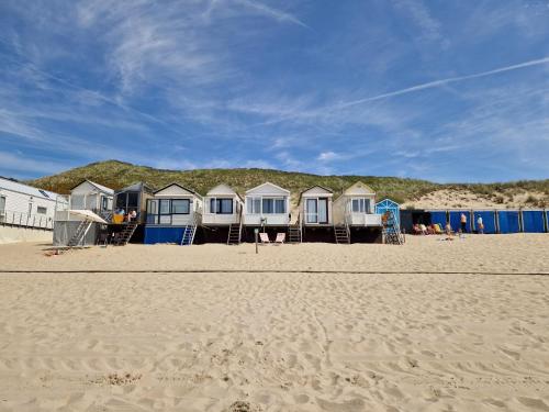 una fila de cabañas de playa en una playa de arena en Slaapstrandhuisje Sleeping Beach House 676 Dishoek aan Zee, en Dishoek