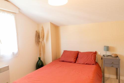 1 dormitorio con cama con sábanas de color naranja y ventana en Maison au cœur du Pays Basque, en Cambo-les-Bains