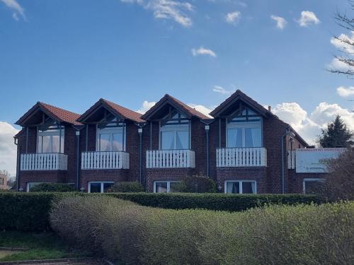 a brown brick house with windows and bushes at Nordseehaus Dangast in Dangast