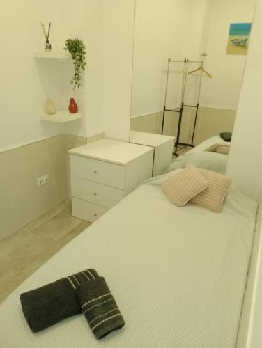 Un dormitorio blanco con una cama con una pajarita negra. en HABITACION INDIVIDUAL, en Sevilla