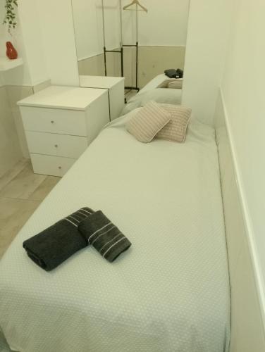 Una cama blanca con un sombrero negro. en HABITACION INDIVIDUAL, en Sevilla