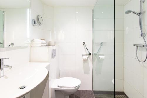 a bathroom with a toilet and a glass shower at Van der Valk Drachten in Drachten