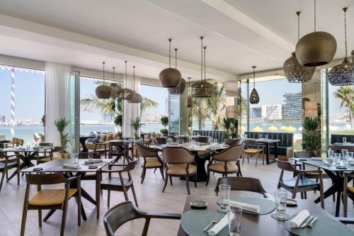 a restaurant with tables and chairs and windows at Vacay Lettings - Private Beach Access -Emaar Beachfront in Dubai