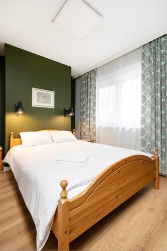 a bedroom with a large bed and a green wall at Rudzka Góra Comfy Apartment by BookingHost in Łódź