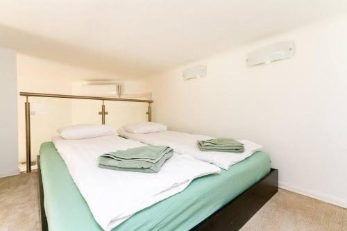 - une chambre avec 2 lits avec des draps blancs et verts dans l'établissement Bright Design Riverside Studio by NW, à Budapest