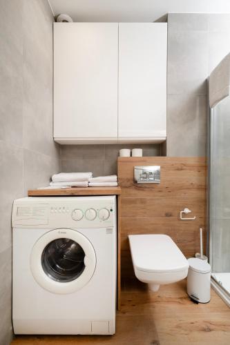 a white washing machine in a bathroom with a toilet at Rudzka Góra Comfy Apartment by BookingHost in Łódź