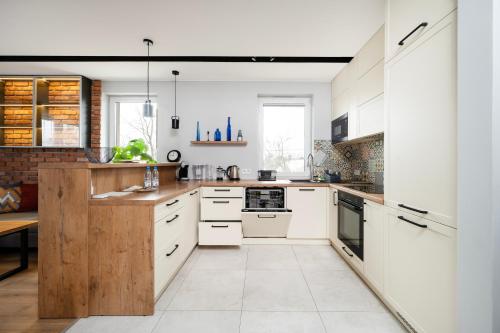 una cucina con armadietti bianchi ed elettrodomestici bianchi di Rudzka Góra Comfy Apartment a Łódź