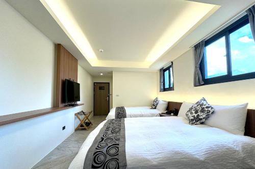 a bedroom with two beds and a flat screen tv at Dafong Hotel in Zhongzheng