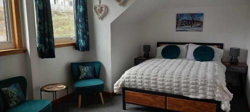 a bedroom with a bed and two blue chairs at Don Muir Guesthouse in Oban