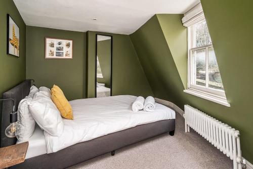 ein Schlafzimmer mit grünen Wänden und ein Bett mit Handtüchern in der Unterkunft Beautiful Central 2 Bed Flat in Bath