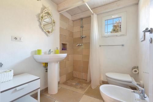 een badkamer met een wastafel, een toilet en een douche bij Trullo Mandorlo by BarbarHouse in Carovigno