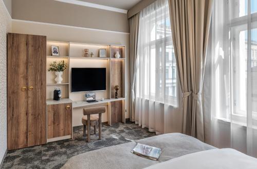 a bedroom with a desk with a television and a bed at Hotel Maestro by Adrez in Prague