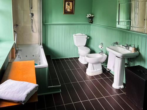 a green bathroom with two toilets and a sink at New Hall, Elland in Elland