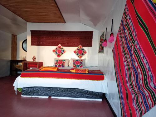 1 dormitorio con 1 cama grande y almohadas coloridas en Laguna del Titicaca lodge, en Puno