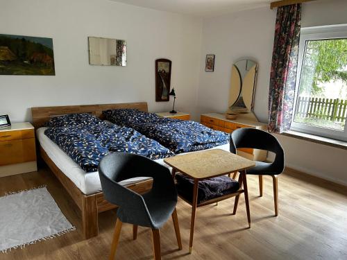 een slaapkamer met een bed en 2 stoelen en een tafel bij Urlaub im Grünen in Stahnsdorf