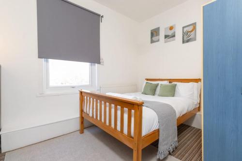a bedroom with a bed with white sheets and a window at Spacious 4 bed in Coventry City Centre, Sleeps up to 7. in Parkside