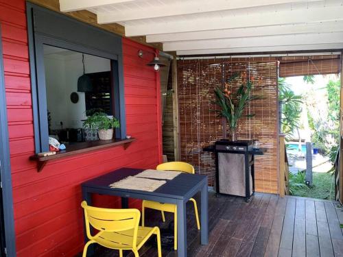 een patio met een tafel en stoelen aan een rode muur bij Ti Cottage sous les Tropiques in Les Avirons