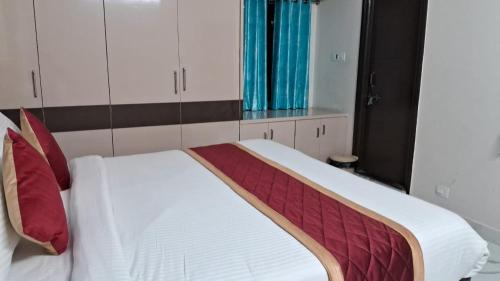 een wit bed met rode kussens in een kamer bij 7HILLSHOMESTAY in Tirupati