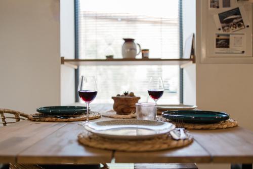 a wooden table with two glasses of red wine at Maisonnette jardin jacuzzi au cœur de Chambles in Chambles