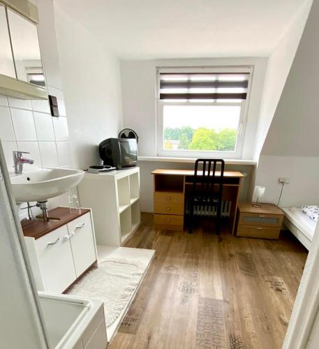 a bathroom with a sink and a desk and a window at Pension Zum Burggrafen in Delmenhorst