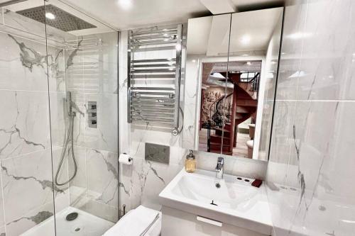 a white bathroom with a sink and a shower at Rooftop Triplex with Garden at Notre Dame in Paris