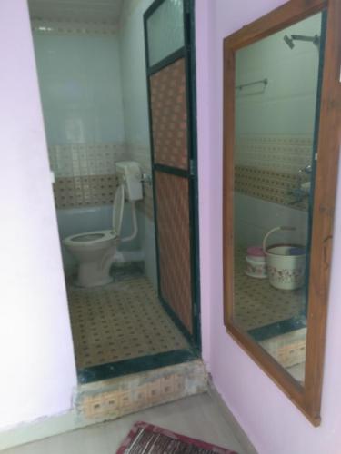 a bathroom with a toilet and a mirror at Advait Holiday Home in Nagaon